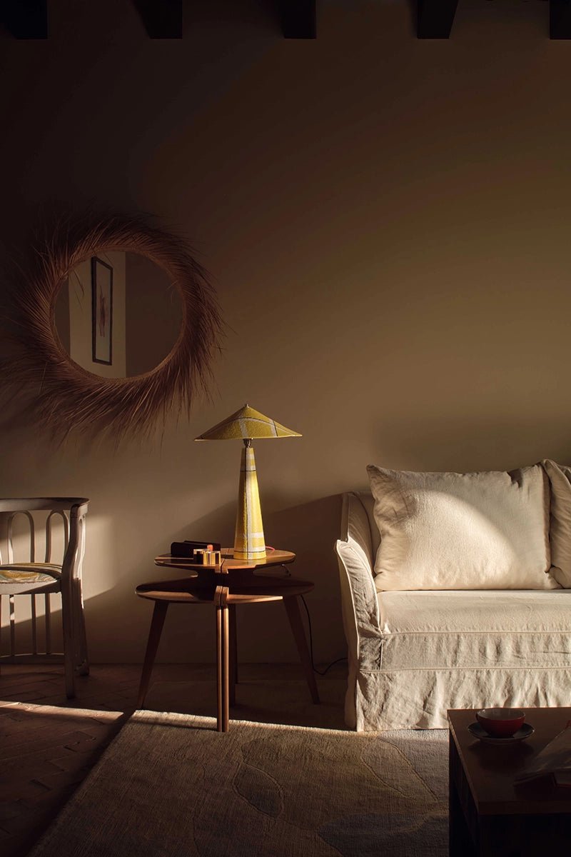 Cozy living room with a yellow geometric lamp on a side table and a sofa with pillows.