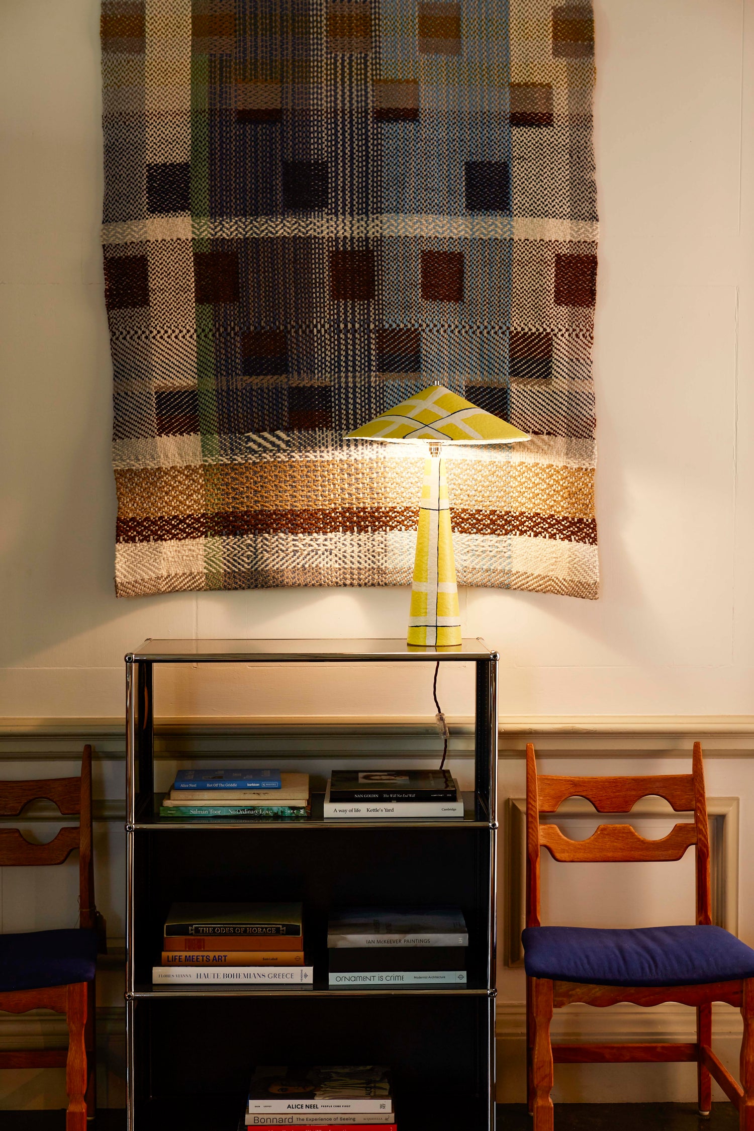 Parasol table lamp made of hand-painted paper pulp in yellow Axis pattern with bulb on in a living room setting