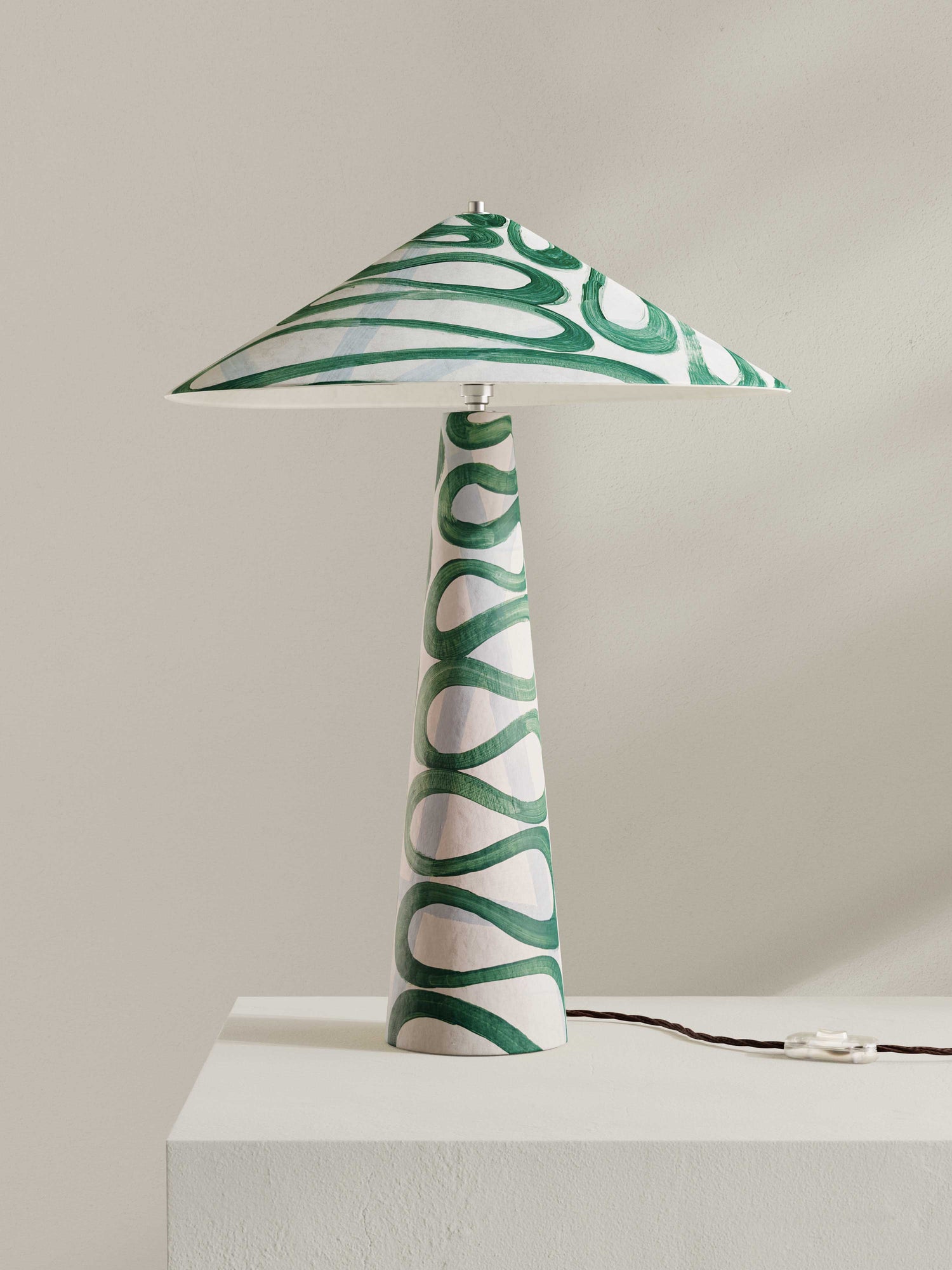 Parasol table lamp with tall stem and wide shade, made of hand-painted paper pulp in swirling green Serpent pattern