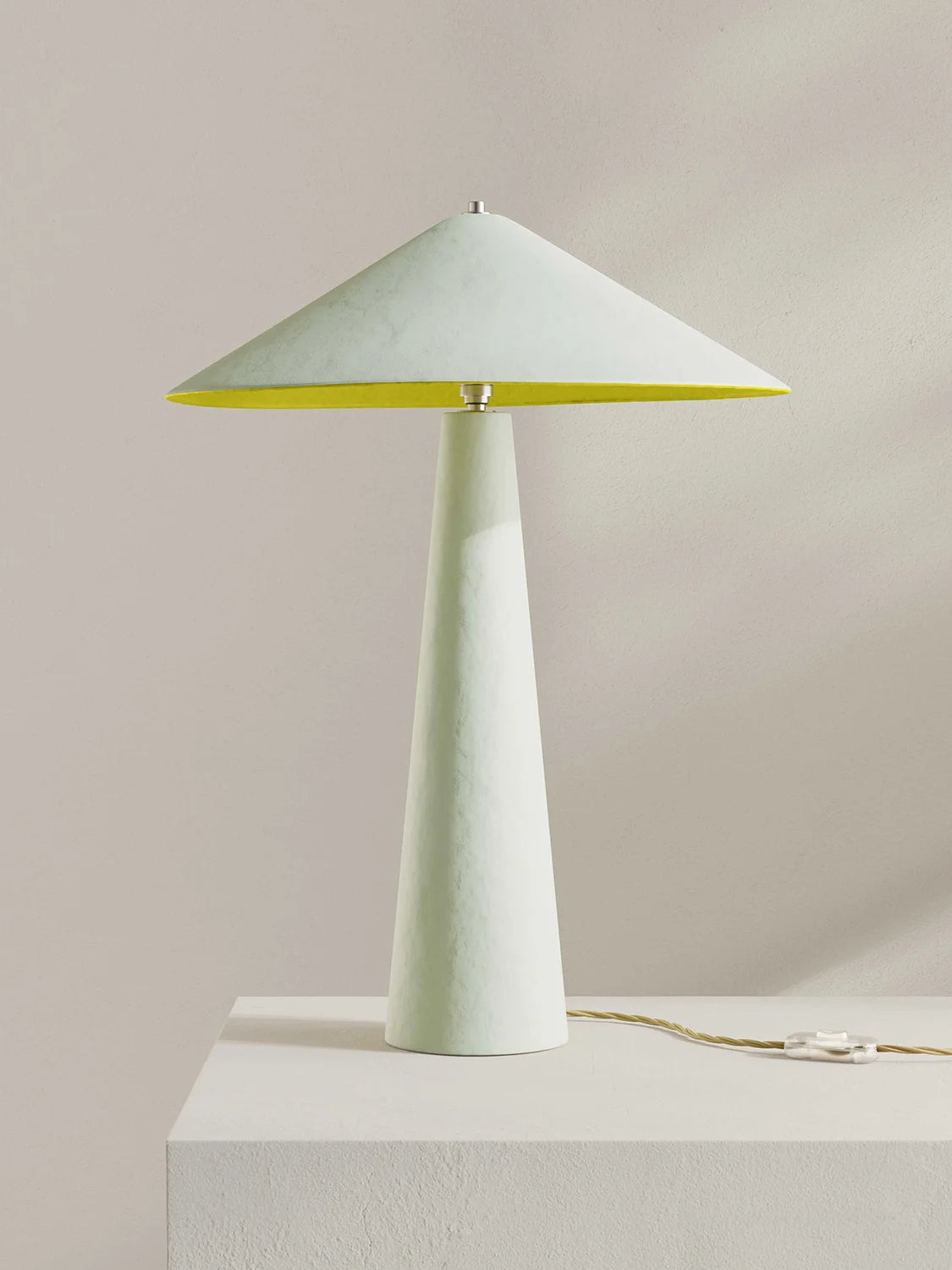 Table lamp with a white base and yellow shade interior on a light gray background