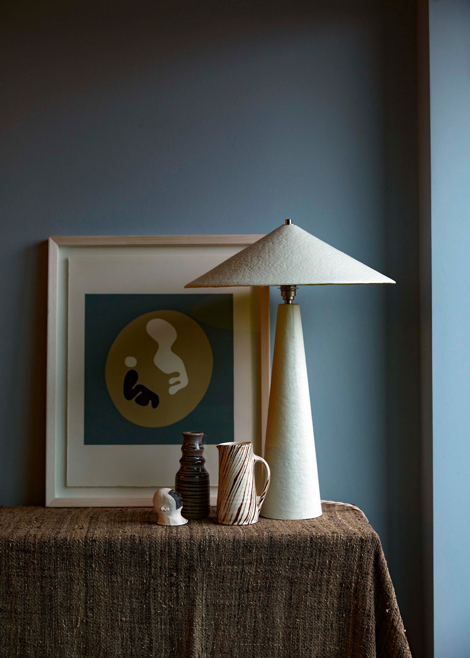 Parasol table lamp, made of paper pulp, hand-painted in off-white on sideboard in home interior.
