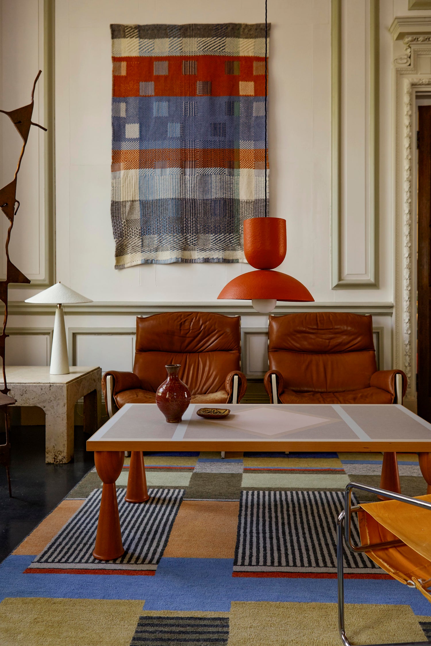 Parasol table lamp in off-white and Buoy pendant ceiling light in orange/red, in living room setting.