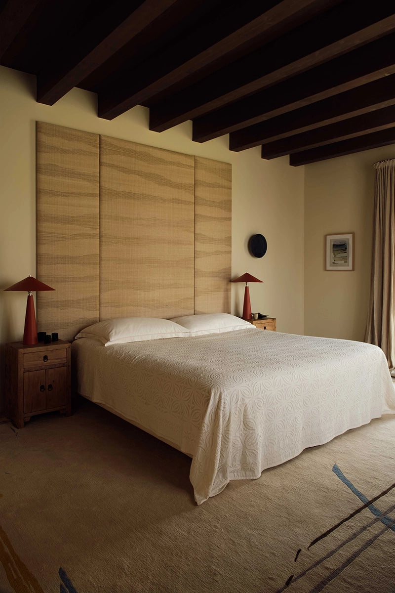 Bedroom with a bed, nightstands, and lamps against a wooden panel wall.