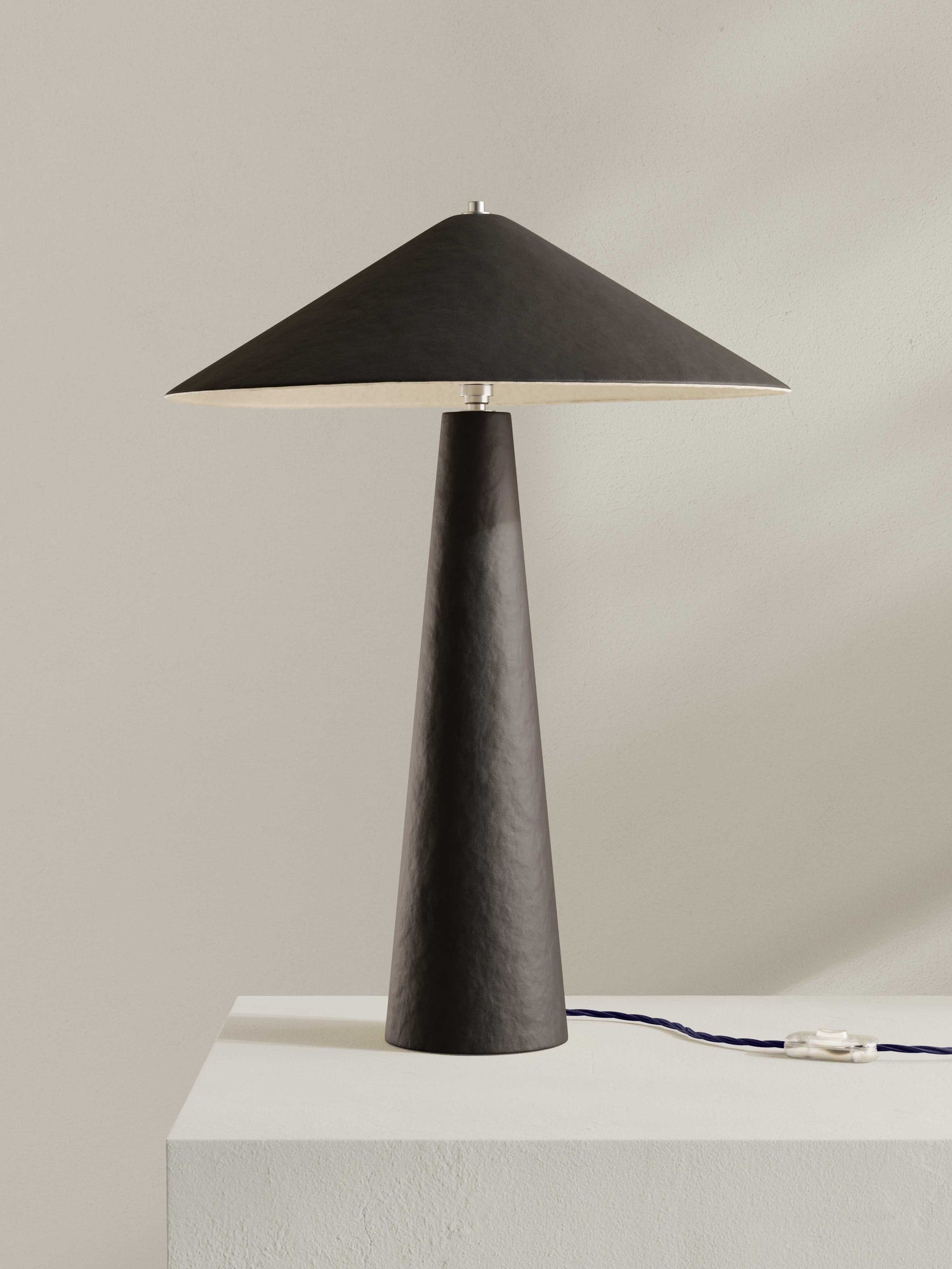 Parasol table lamp with tall stem and wide shade, made of hand-painted paper pulp in dark brown.
