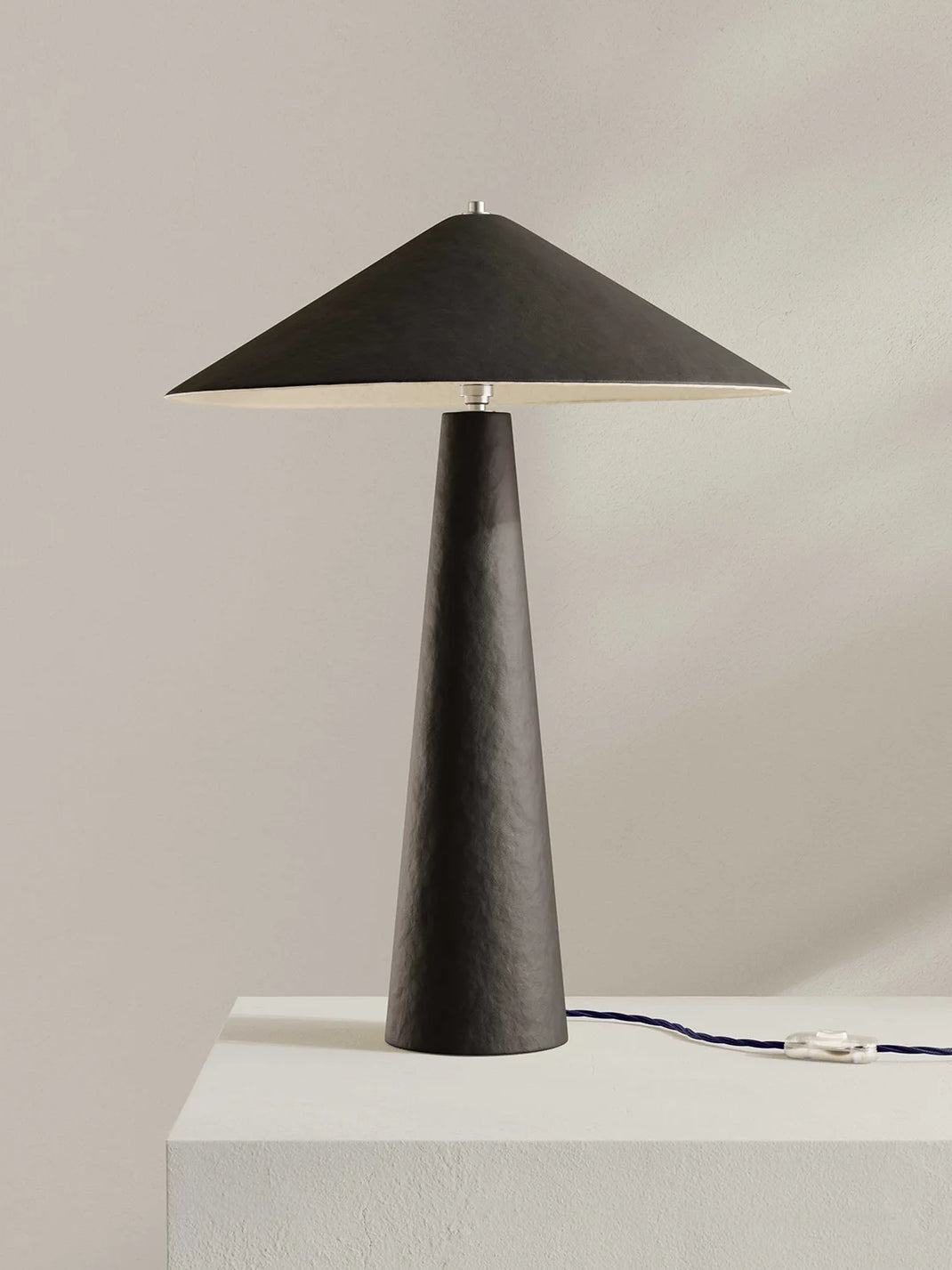 Dark brown table lamp with a conical design on a light gray background