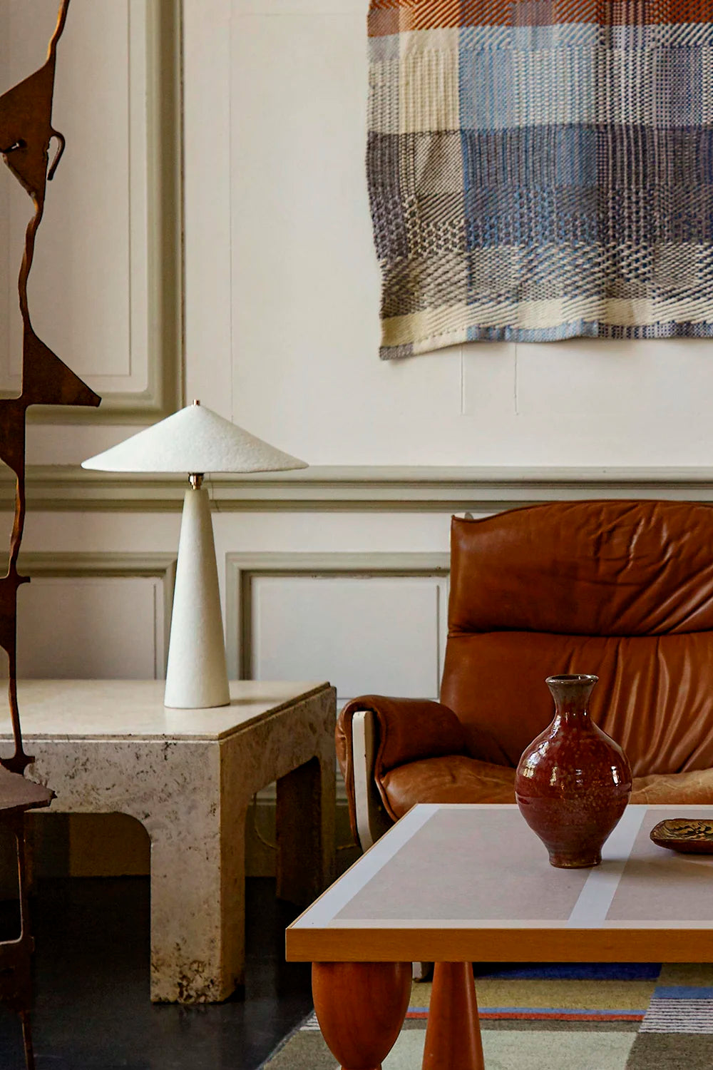 Living room with a brown leather chair, white table lamp, and decorative rug.