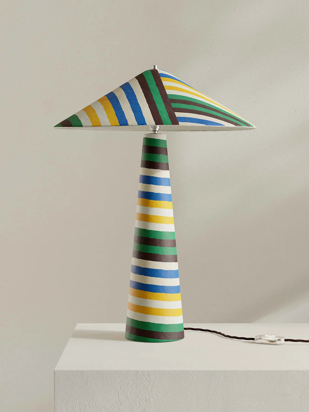 Colorful striped lamp on a white surface with a plain background