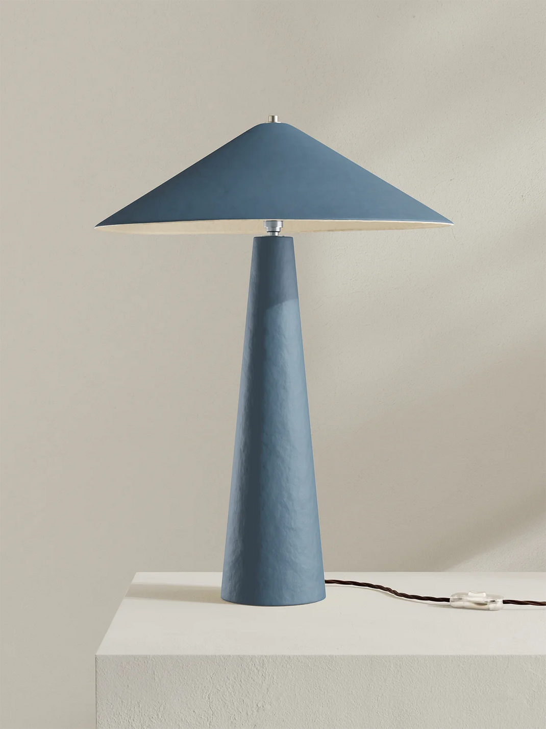 Blue table lamp with a conical base and rectangular shade on a neutral background
