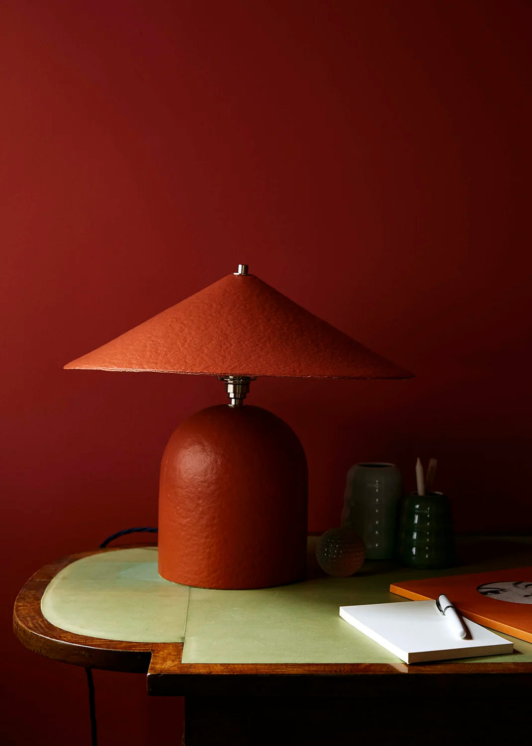 Red table lamp on a wooden table against a red wall