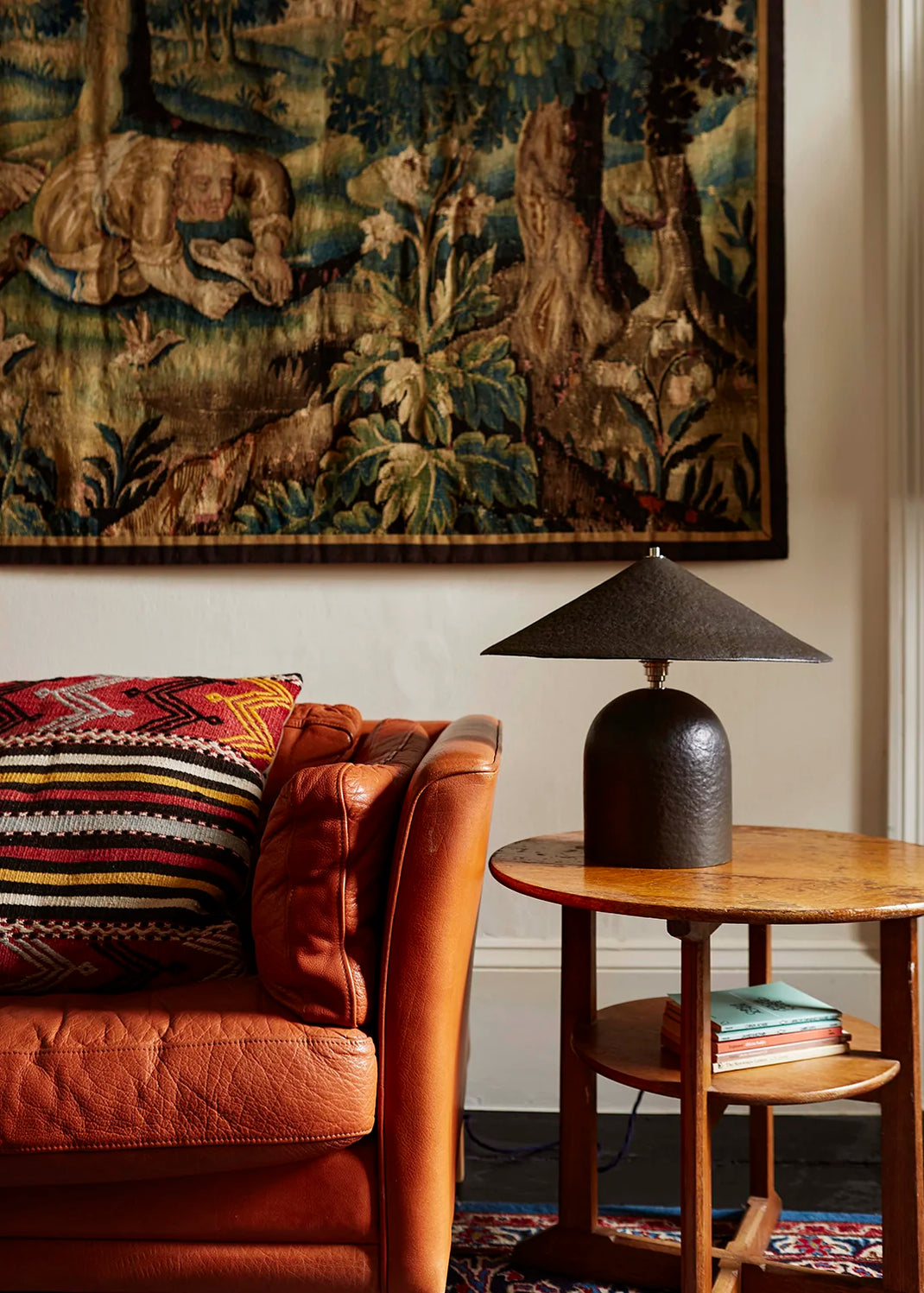 Living room with brown leather sofa, brown table lamp, patterned rug, and tapestry on the wall.