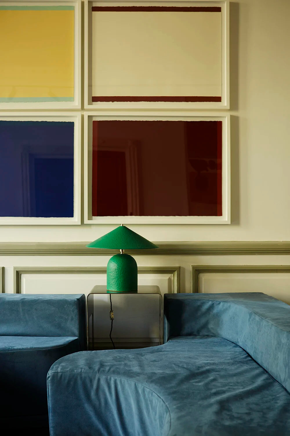 Green lamp on a coffee table with framed abstract art on the wall