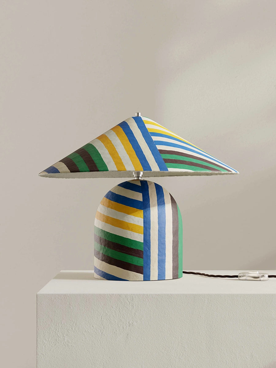 Colorful striped table lamp on a white surface with a neutral background