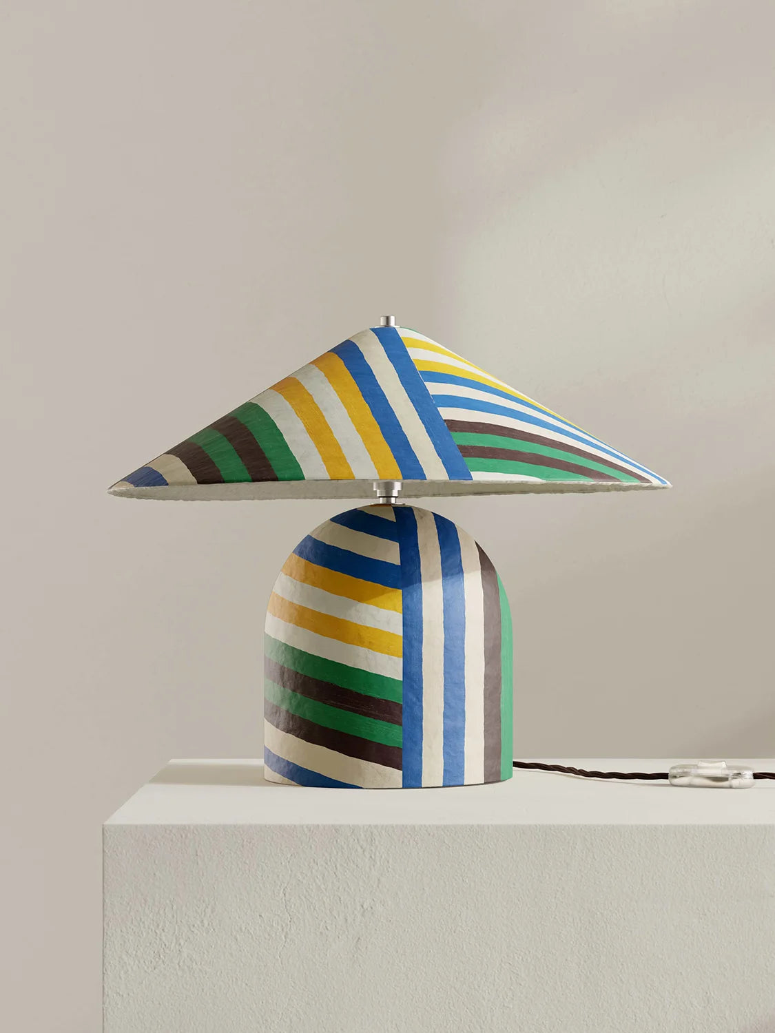 Colorful striped table lamp on a white surface with a neutral background