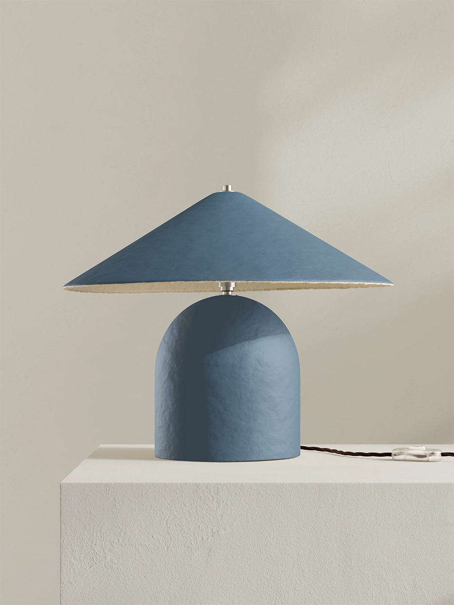Blue table lamp with a textured base on a light gray surface against a beige background