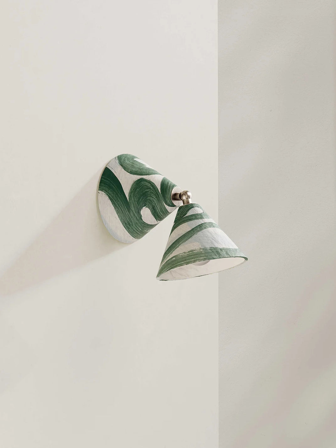 Wall-mounted lamp with green and white pattern on a plain wall