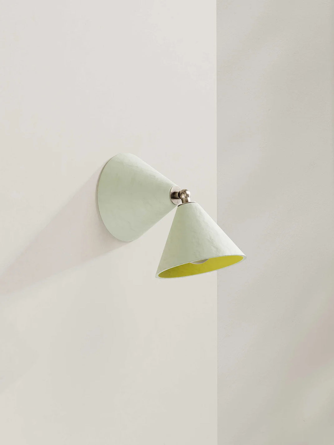 A modern wall-mounted cone-shaped sconce in an off-white finish with a contrasting yellow interior, shown mounted on a neutral wall.