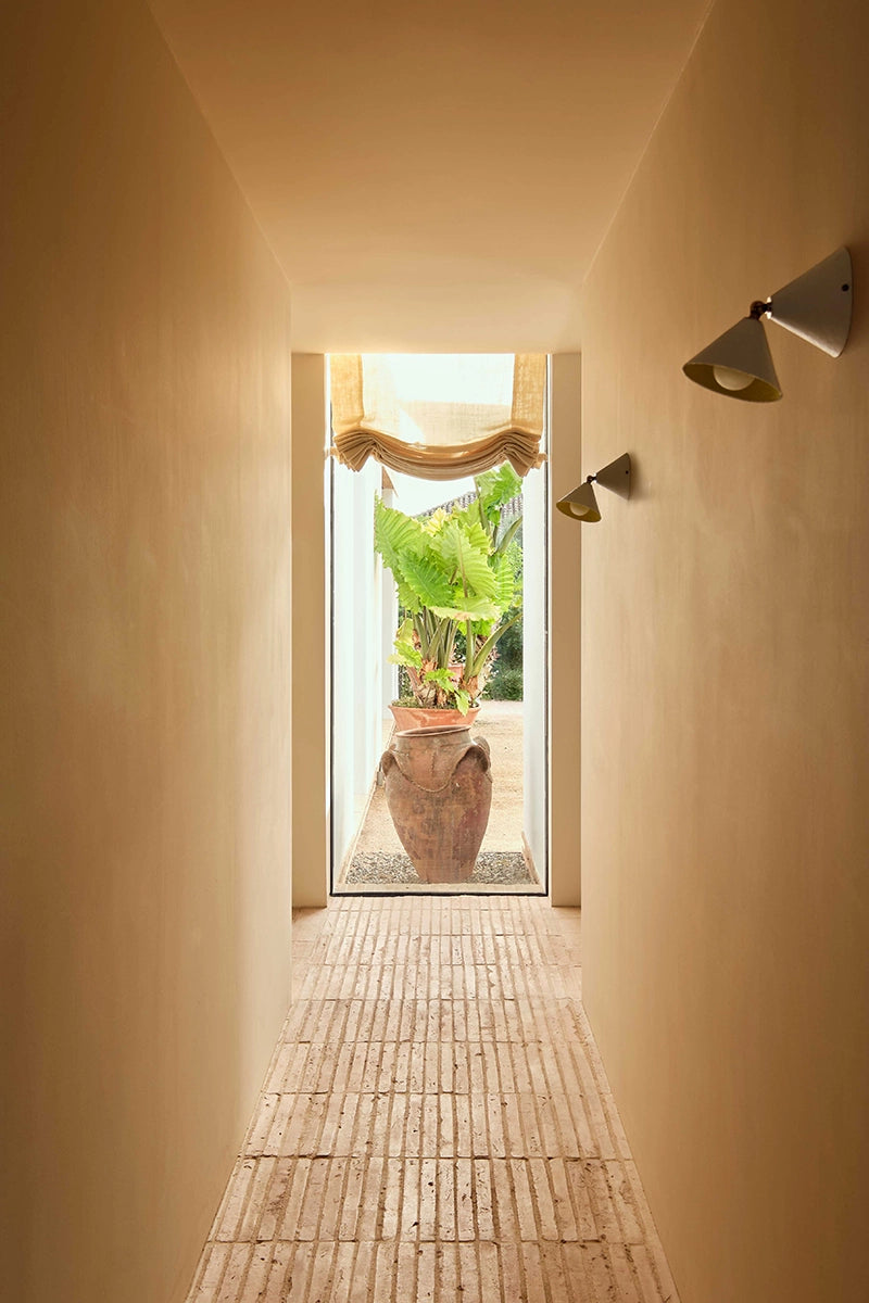 Hallway with a window at the end, and 2 wall lamps along the right wall