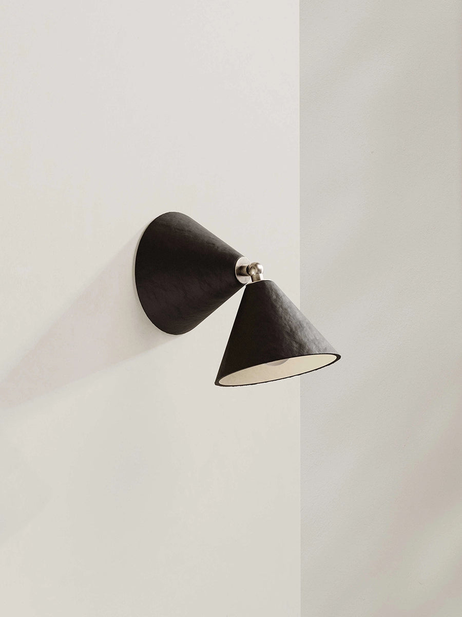 Brown-black wall-mounted lamp on a light gray wall