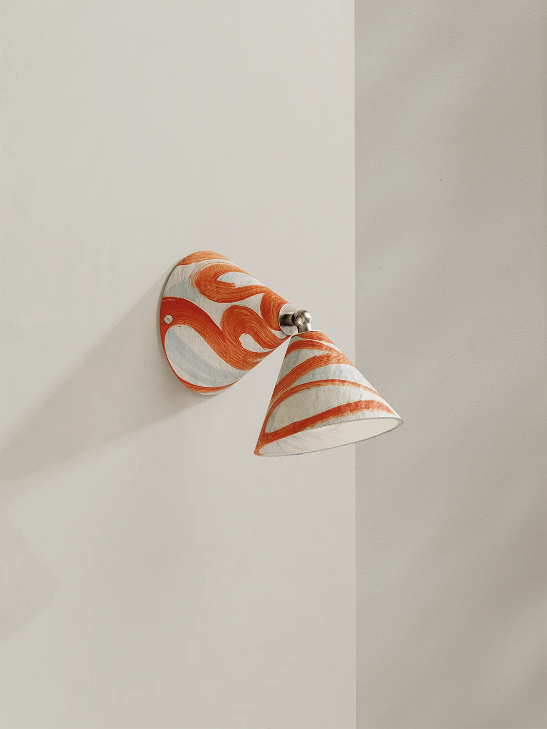 Wall-mounted lamp with an orange and white pattern on a plain wall