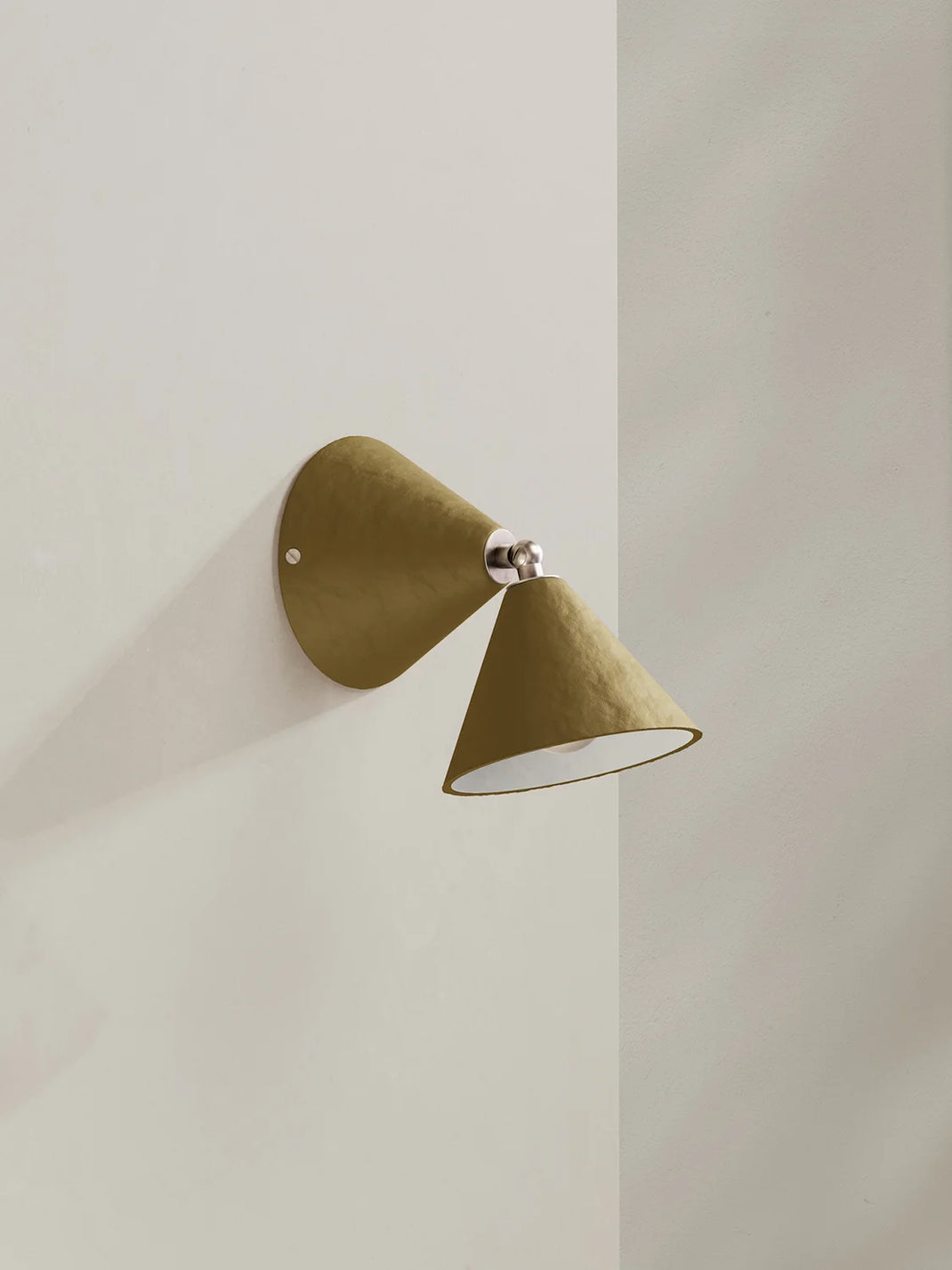A modern wall sconce with two textured olive green cone-shaped shades and a polished silver metal joint, shown mounted on a minimalist off-white wall.