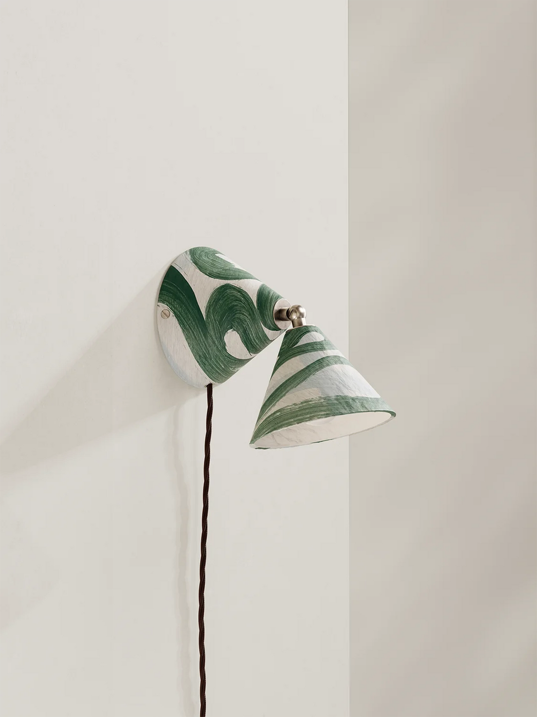 A modern wall-mounted sconce with a white body featuring a green marbled swirl pattern, shown mounted on a plain off-white wall.