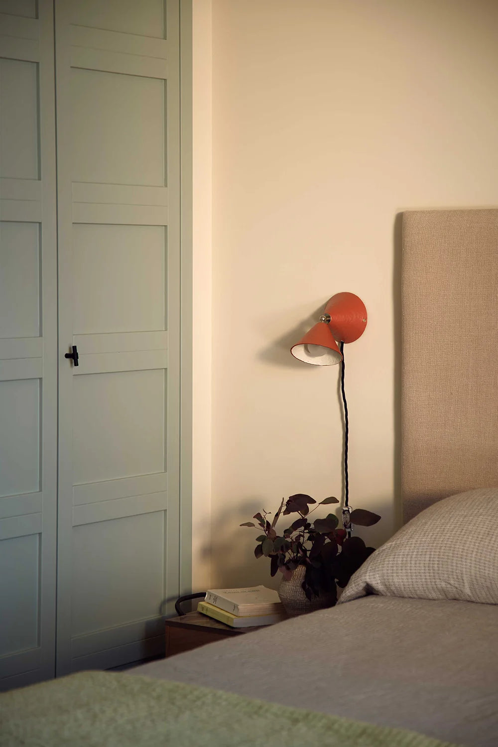 Bedroom with a bed, nightstand, and wall lamp.