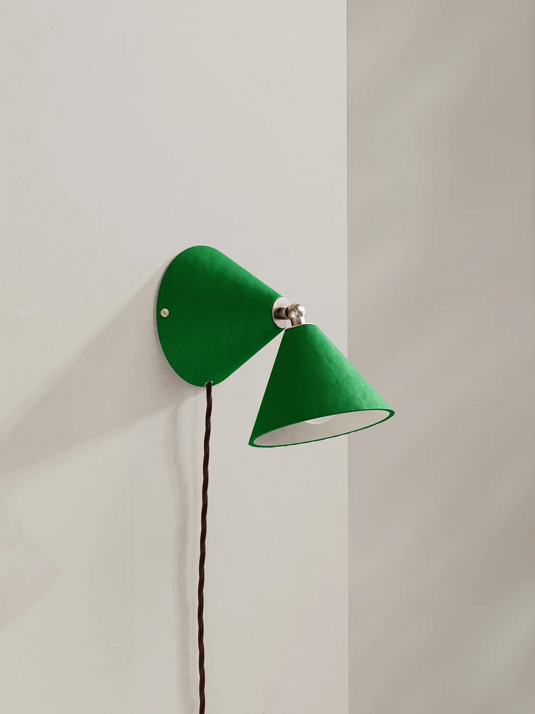 A green wall-mounted lamp with two cone-shaped shades, shown mounted on a plain off-white wall.