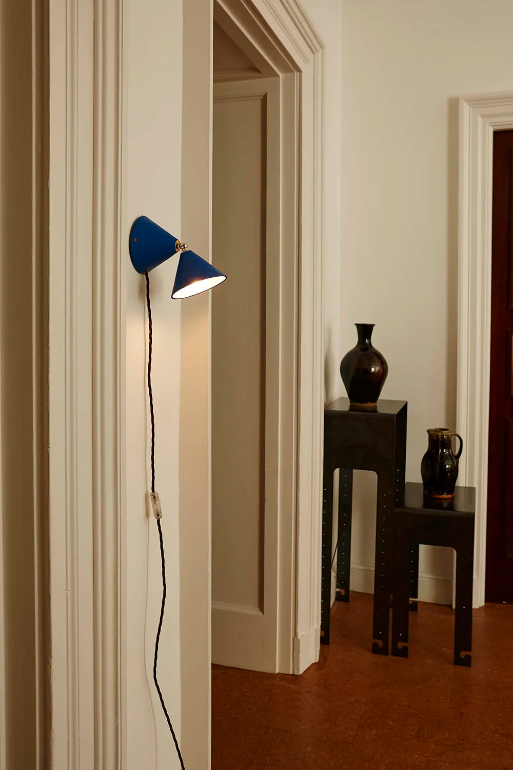 Blue wall lamp in a room with a vase and other decor items on a table.