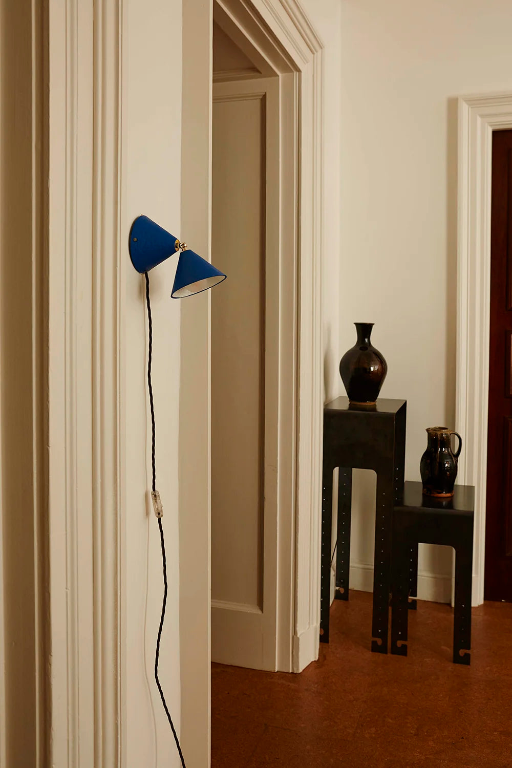 Blue wall lamp in a room with a vase and other decor items on a table.