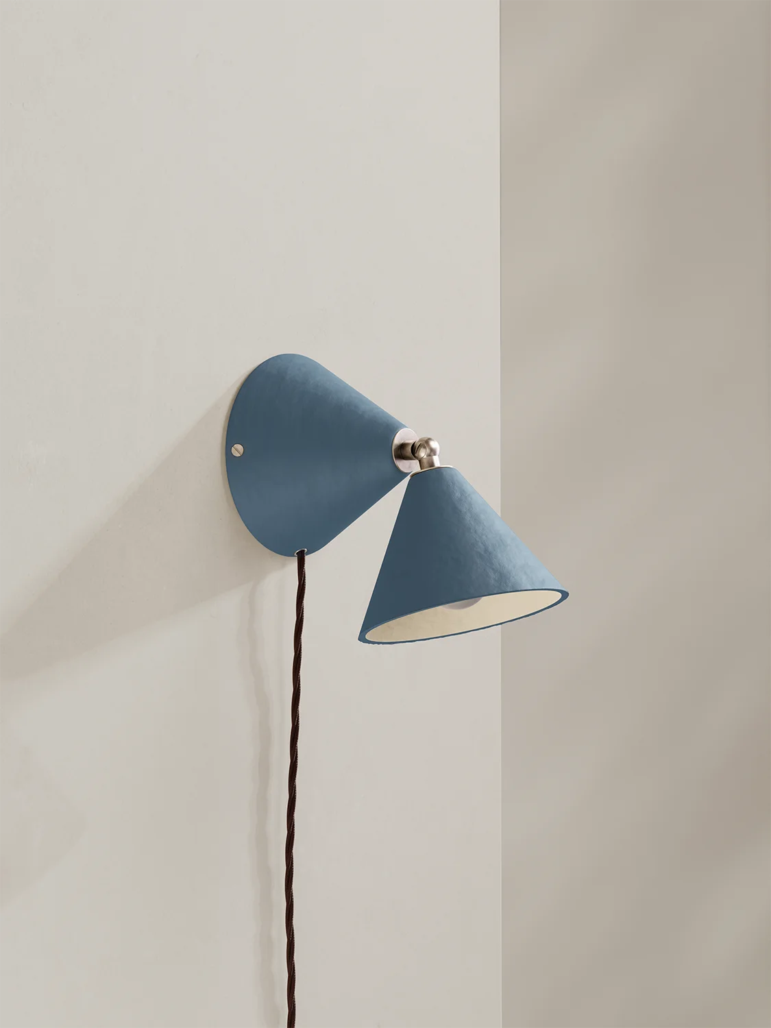 Blue wall lamp with a white bulb against a light gray wall
