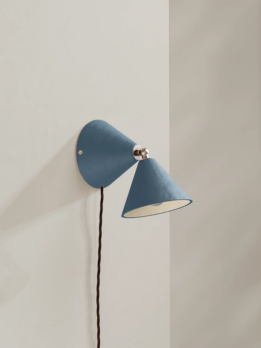 Blue wall lamp with a white bulb against a light gray wall
