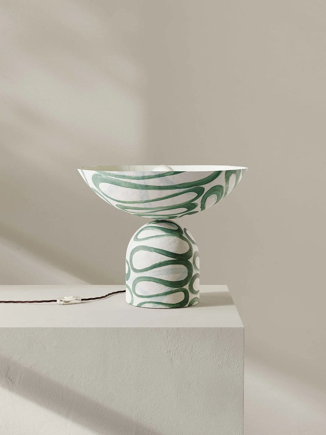 Uplighter table lamp with green abstract patterns on a neutral background