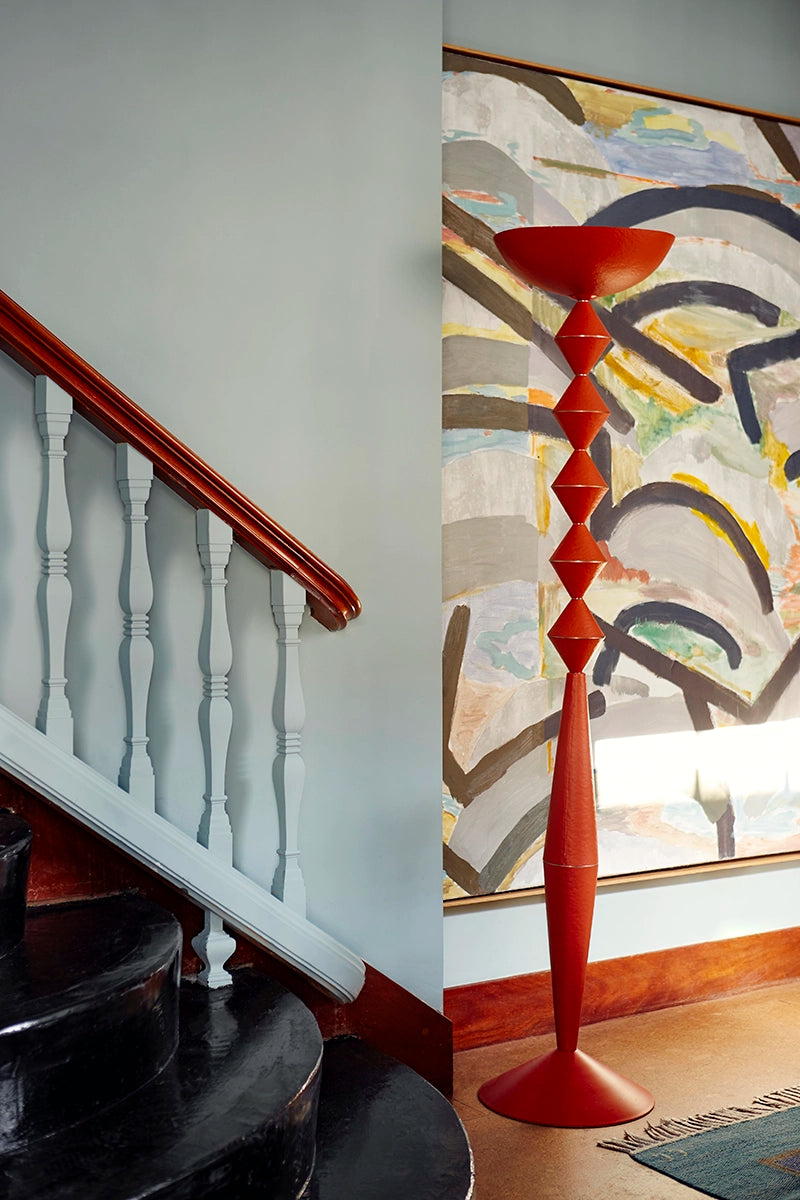 Geometric floor lamp in orange against a colourful painting