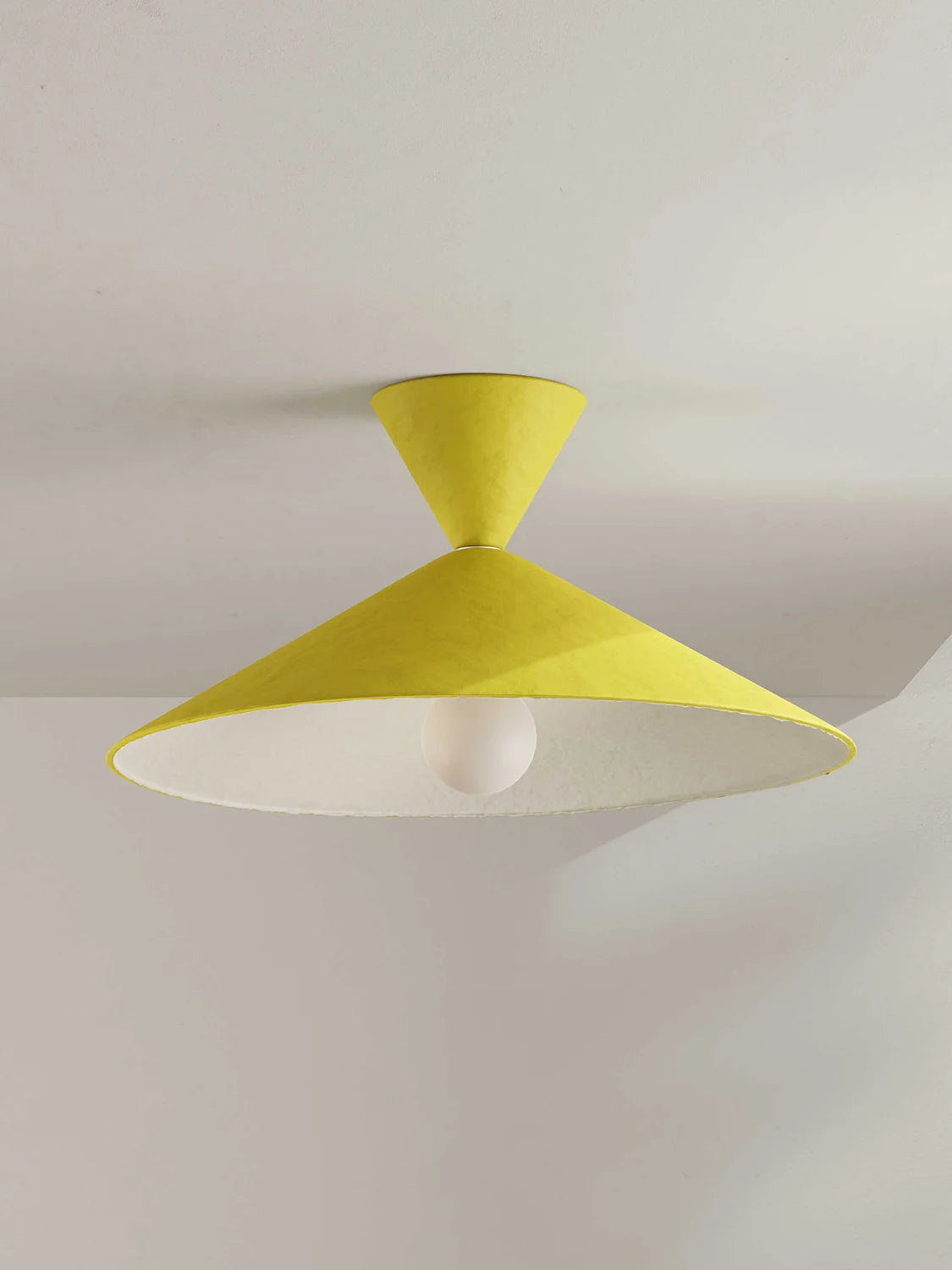 A modern ceiling light fixture with a bright yellow cone-shaped shade and a white interior, mounted on a white ceiling.