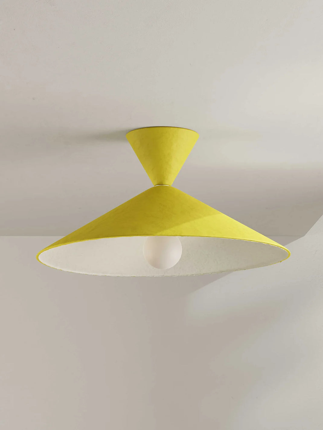 A modern ceiling light fixture with a bright yellow cone-shaped shade and a white interior, mounted on a white ceiling.