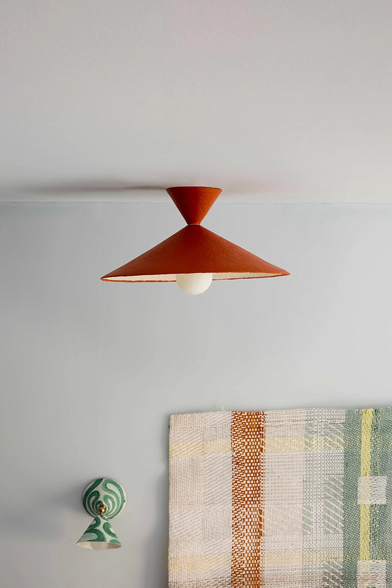 Ceiling light fixture on a white wall with a decorative wall hanging.